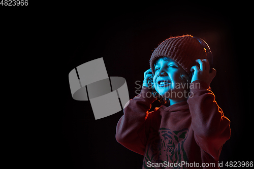 Image of Caucasian boy\'s portrait isolated on dark studio background in neon light