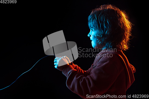 Image of Caucasian boy\'s portrait isolated on dark studio background in neon light