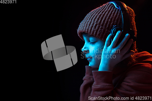 Image of Caucasian boy\'s portrait isolated on dark studio background in neon light