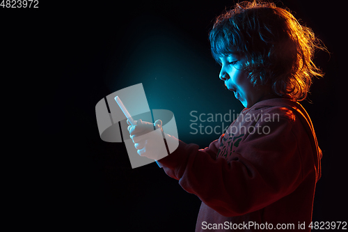 Image of Caucasian boy\'s portrait isolated on dark studio background in neon light