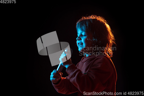 Image of Caucasian boy\'s portrait isolated on dark studio background in neon light