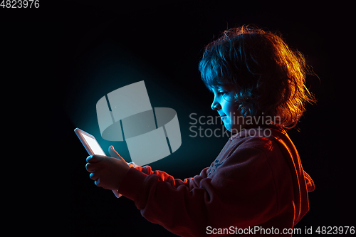 Image of Caucasian boy\'s portrait isolated on dark studio background in neon light