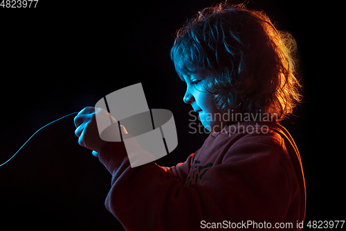 Image of Caucasian boy\'s portrait isolated on dark studio background in neon light