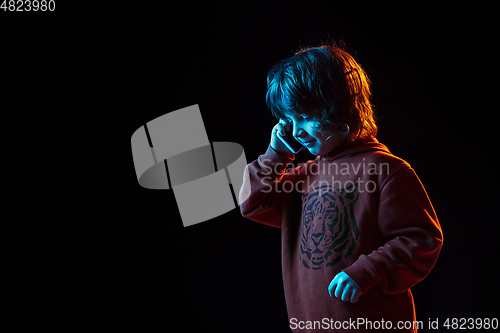 Image of Caucasian boy\'s portrait isolated on dark studio background in neon light