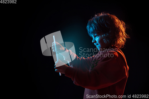 Image of Caucasian boy\'s portrait isolated on dark studio background in neon light