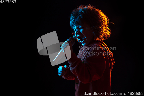 Image of Caucasian boy\'s portrait isolated on dark studio background in neon light