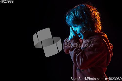 Image of Caucasian boy\'s portrait isolated on dark studio background in neon light