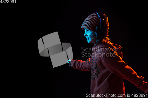 Image of Caucasian boy\'s portrait isolated on dark studio background in neon light