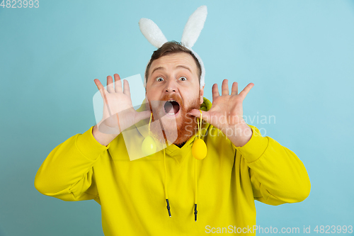 Image of Easter bunny man with bright emotions on blue studio background