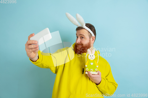 Image of Easter bunny man with bright emotions on blue studio background