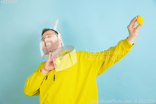 Image of Easter bunny man with bright emotions on blue studio background