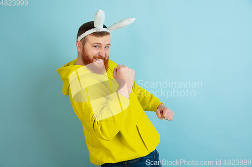 Image of Easter bunny man with bright emotions on blue studio background