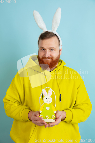 Image of Easter bunny man with bright emotions on blue studio background