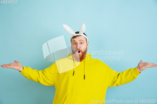 Image of Easter bunny man with bright emotions on blue studio background