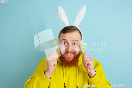 Image of Easter bunny man with bright emotions on blue studio background