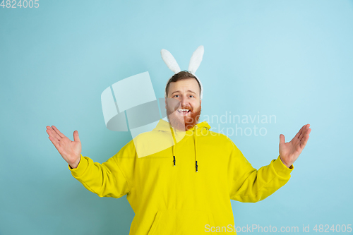 Image of Easter bunny man with bright emotions on blue studio background