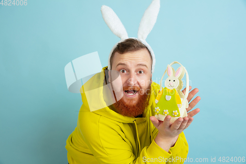 Image of Easter bunny man with bright emotions on blue studio background