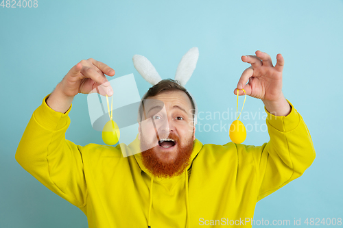 Image of Easter bunny man with bright emotions on blue studio background