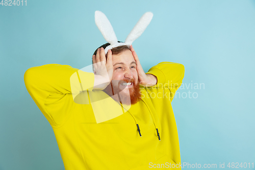 Image of Easter bunny man with bright emotions on blue studio background