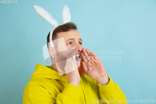 Image of Easter bunny man with bright emotions on blue studio background