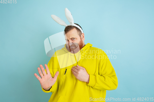 Image of Easter bunny man with bright emotions on blue studio background