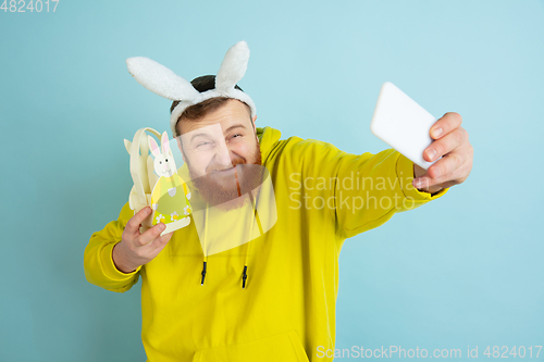 Image of Easter bunny man with bright emotions on blue studio background