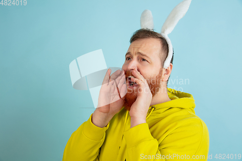 Image of Easter bunny man with bright emotions on blue studio background