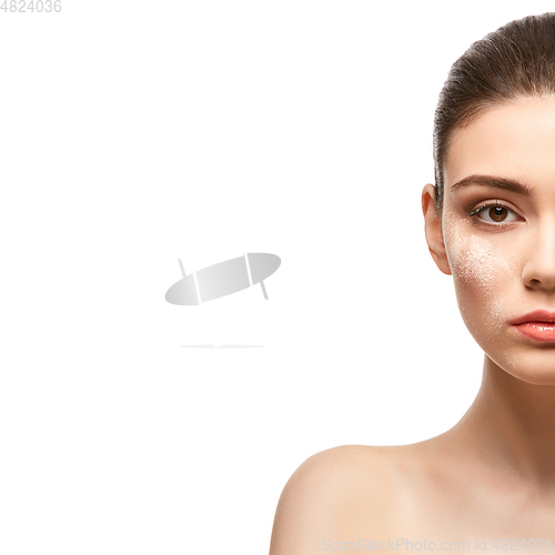 Image of beautiful girl applying powder on face isolated on white