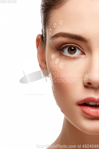 Image of girl applying foundation on face isolated on white