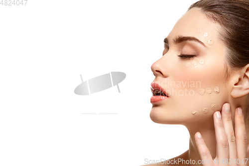 Image of girl applying foundation on face isolated on white