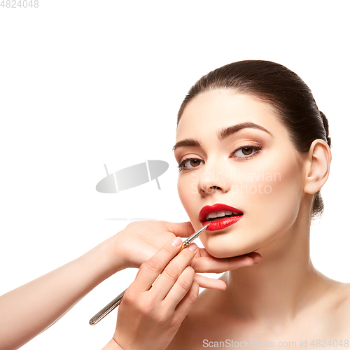 Image of girl applying red lipstick isolated on white