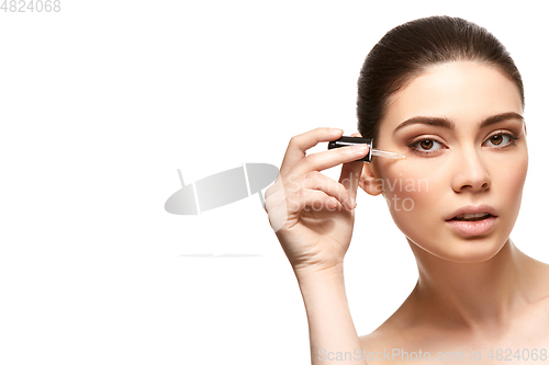 Image of girl applying eye serum isolated on white