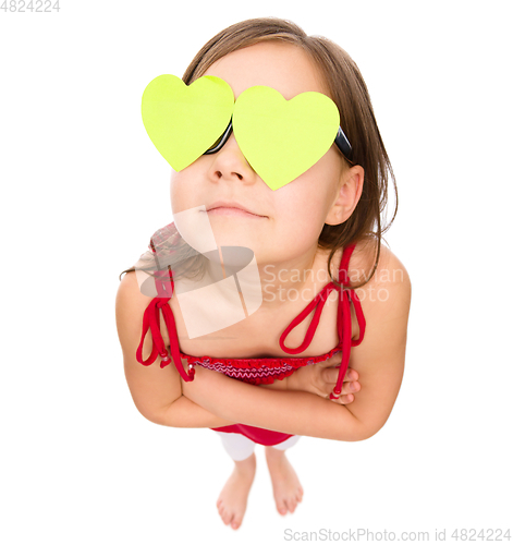 Image of Little girl is holding hearts over her eyes