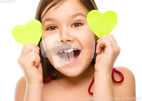 Image of Little girl is holding hearts near her eyes