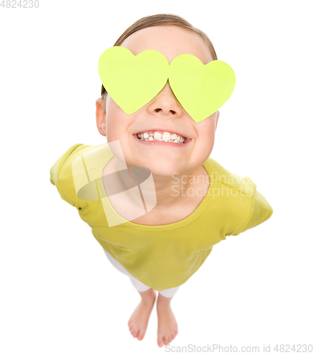 Image of Little girl is holding hearts over her eyes