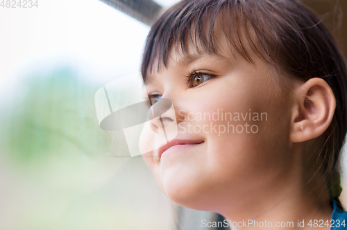 Image of Happy girl is looking through window