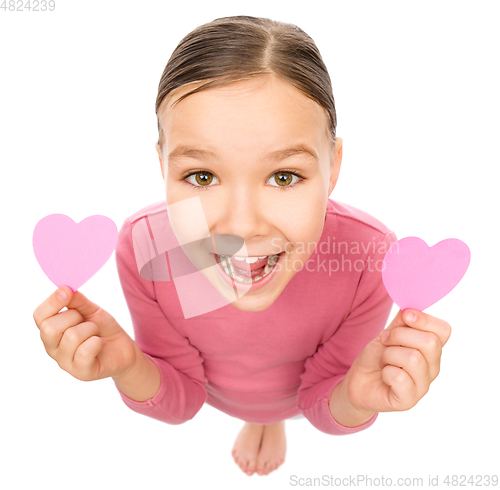 Image of Little girl is holding hearts near her eyes