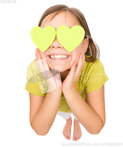 Image of Little girl is holding hearts over her eyes