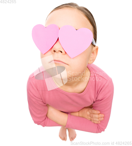 Image of Little girl is holding hearts over her eyes