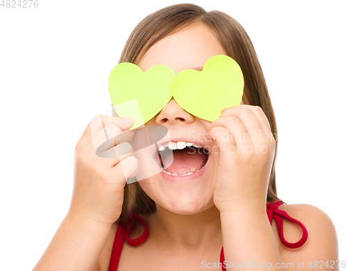 Image of Little girl is holding hearts over her eyes