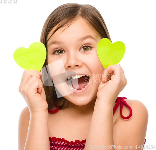 Image of Little girl is holding hearts near her eyes