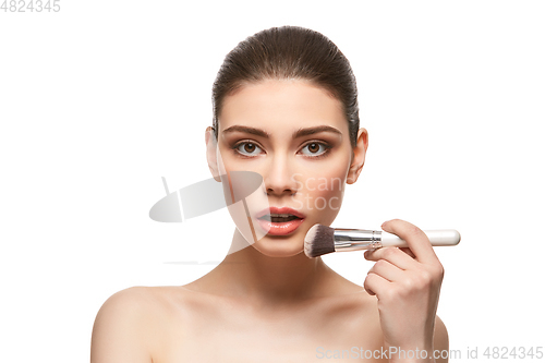 Image of girl applying foundation on face isolated on white