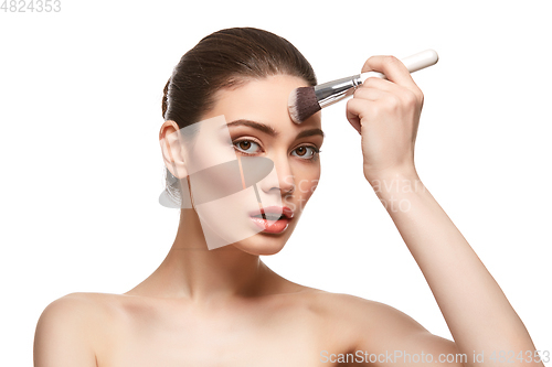 Image of girl applying foundation on face isolated on white