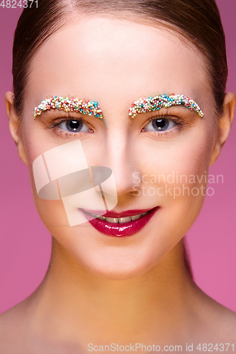 Image of beautiful girl with candies on pink backgroound