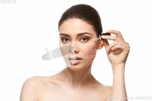 Image of girl applying eye serum isolated on white