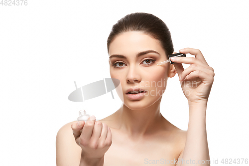 Image of girl applying eye serum isolated on white