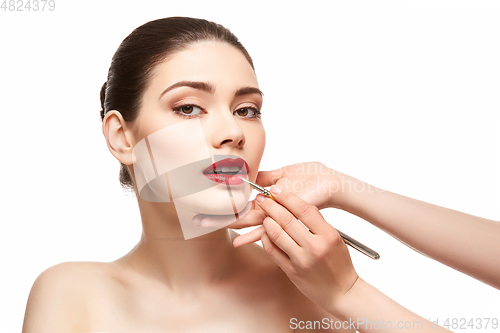 Image of girl applying red lipstick isolated on white