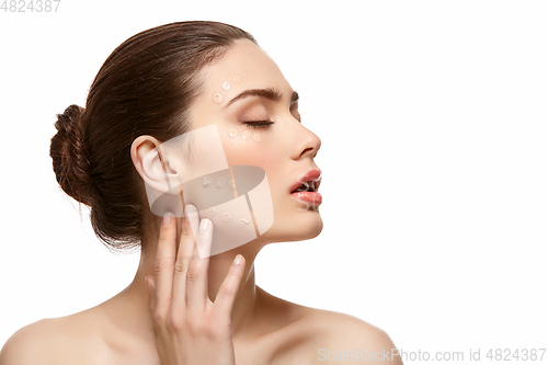 Image of girl applying foundation on face isolated on white