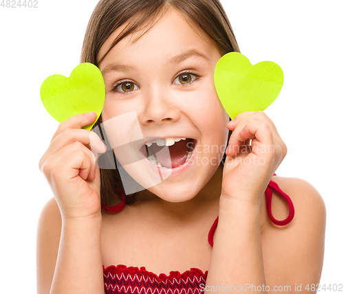 Image of Little girl is holding hearts near her eyes