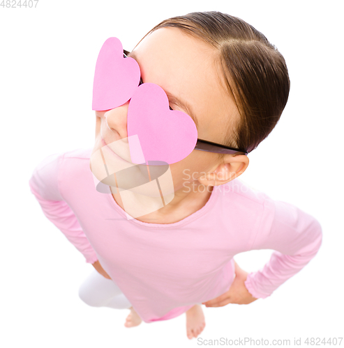 Image of Little girl is holding hearts over her eyes